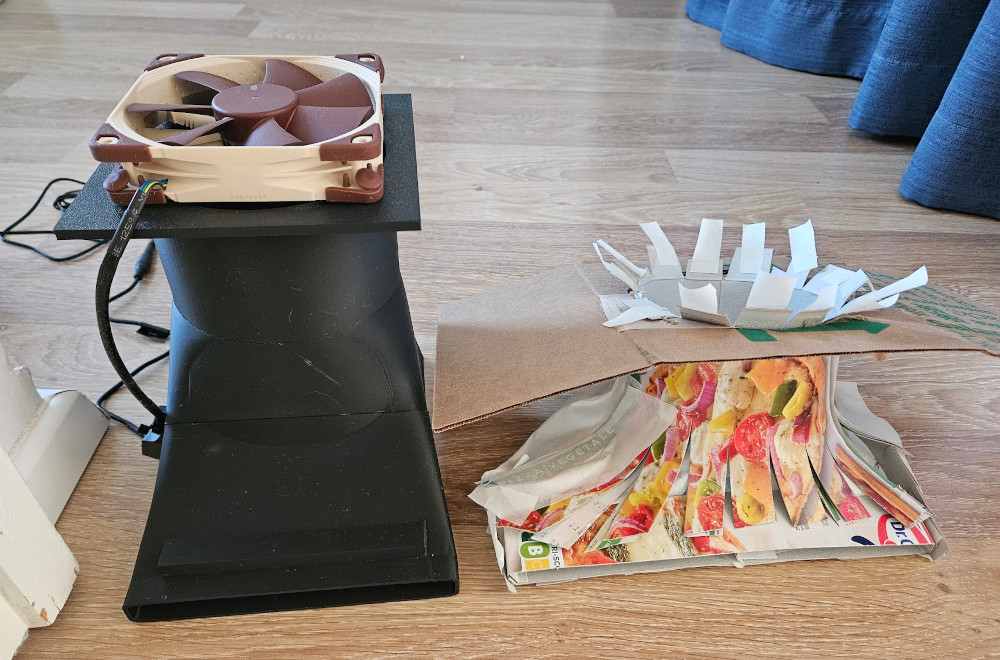 A photo of the large, three-part 3D printed "tower" duct, alonside the pizza box prototype.