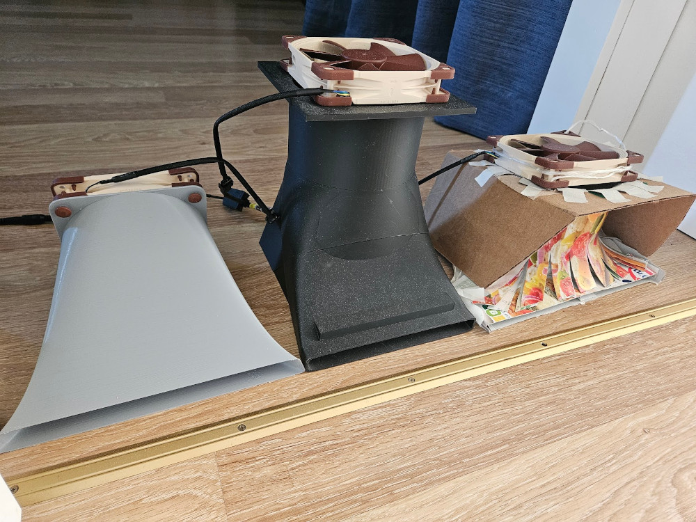 My current setup, from left to right: the new funnel duct (v4), the "defensive tower" (v2), and the original pizza box prototype. The second funnel and the standing fan are not shown.